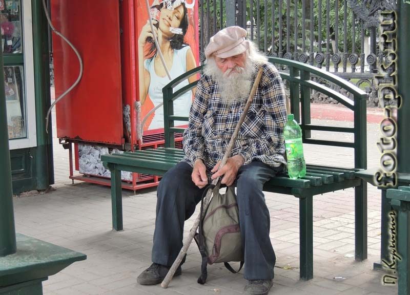 Senior adult man sitting on the bench of a bus stop