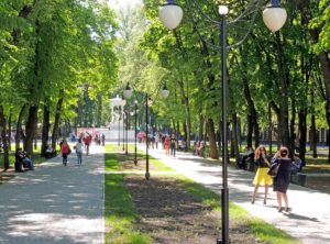 Townsfolk having a walk in the city park at a sunny feast day