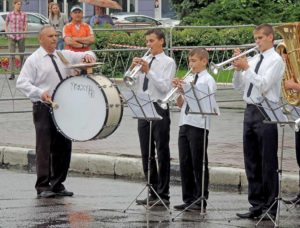 Performance of children's brass band beating in the rain