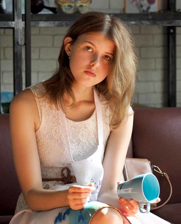 Late teens girl with painted mug. Free activities for adults and children in the creative space "Symbol" in Moscow.