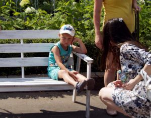 Frustrated elementary age boy sitting on a a park bench, and mother sympathize with him